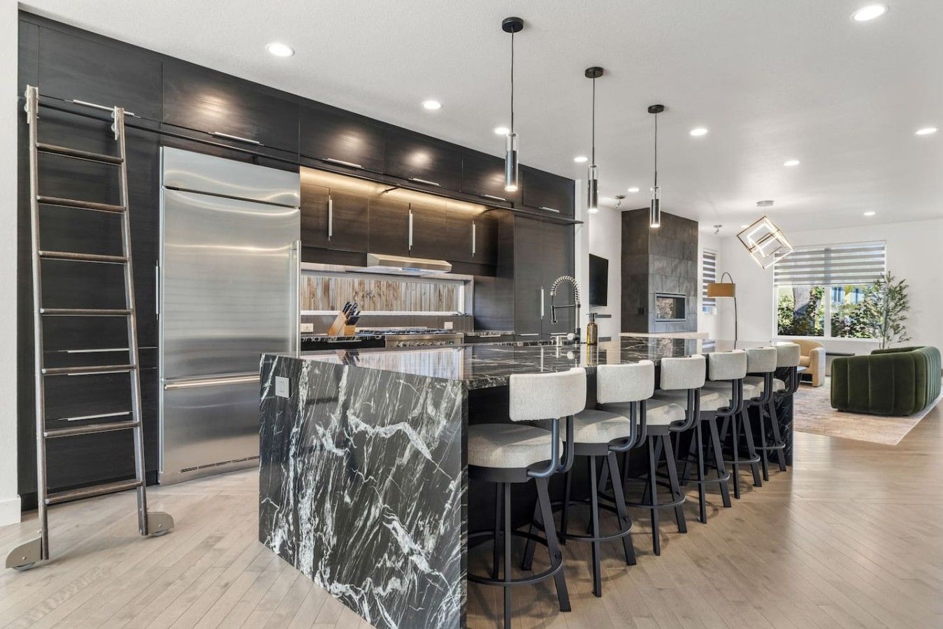 A modern kitchen with a marble island, stainless steel appliances, and a bar area with stools.