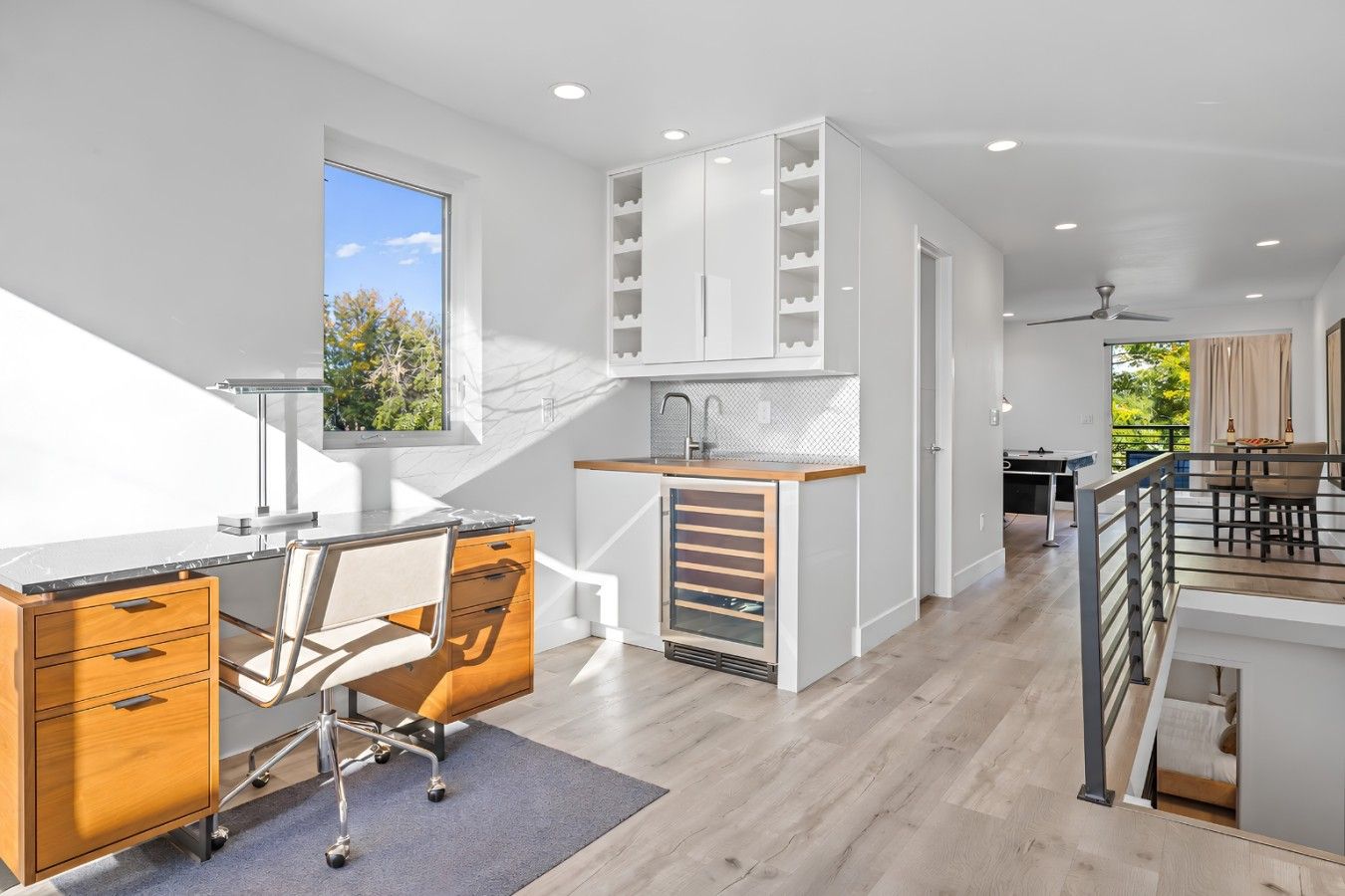 A modern kitchen with a built-in island, a dining area with a table and chairs, and a view of the outdoors through a window.