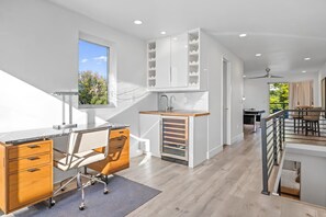 A modern kitchen with a built-in island, a dining area with a table and chairs, and a view of the outdoors through a window. - Denver Designer Retreat | Hot Tub | Rooftop Decks (Denver)