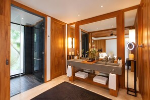 Un bagno moderno con un ampio specchio, elementi in legno, cabina doccia in vetro e un mobile lavabo completo di lavandino e porta asciugamani.