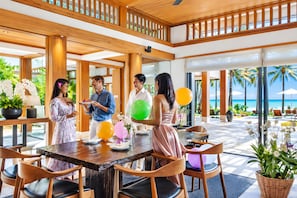 A spacious indoor area with a wooden ceiling and large windows, a dining table with chairs, and a view of the beach outside. - Villa Nandana 7BR/Beachfront/Gym/Maid/BF (Takua Thung)