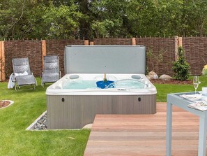 A hot tub with a wooden deck, two lounge chairs, and a table with a glass. - Ankerhaus-darss (Born auf dem Darss)