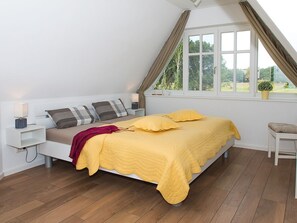 A bedroom with a bed, bedside tables, a window with curtains, and a view of greenery outside. - Ankerhaus-darss (Born auf dem Darss)