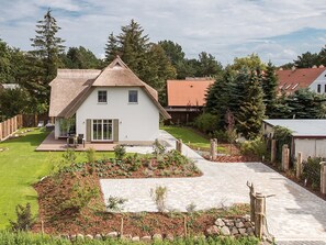 A single-story house with a thatched roof, a front porch, and a well-maintained garden. - Ankerhaus-darss (Born auf dem Darss)