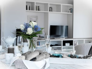 A modern living room with a white sofa, a flat-screen TV, and a bookshelf. - Ankerhaus-darss (Born auf dem Darss)
