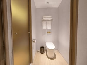 A compact bathroom with a toilet, a trash bin, and a towel rack. - Caelum Gaudia Hotel (Guangzhou)