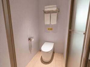 A small, modern bathroom with a toilet, a towel rack, and a sign indicating a small area. - Caelum Gaudia Hotel (Guangzhou)