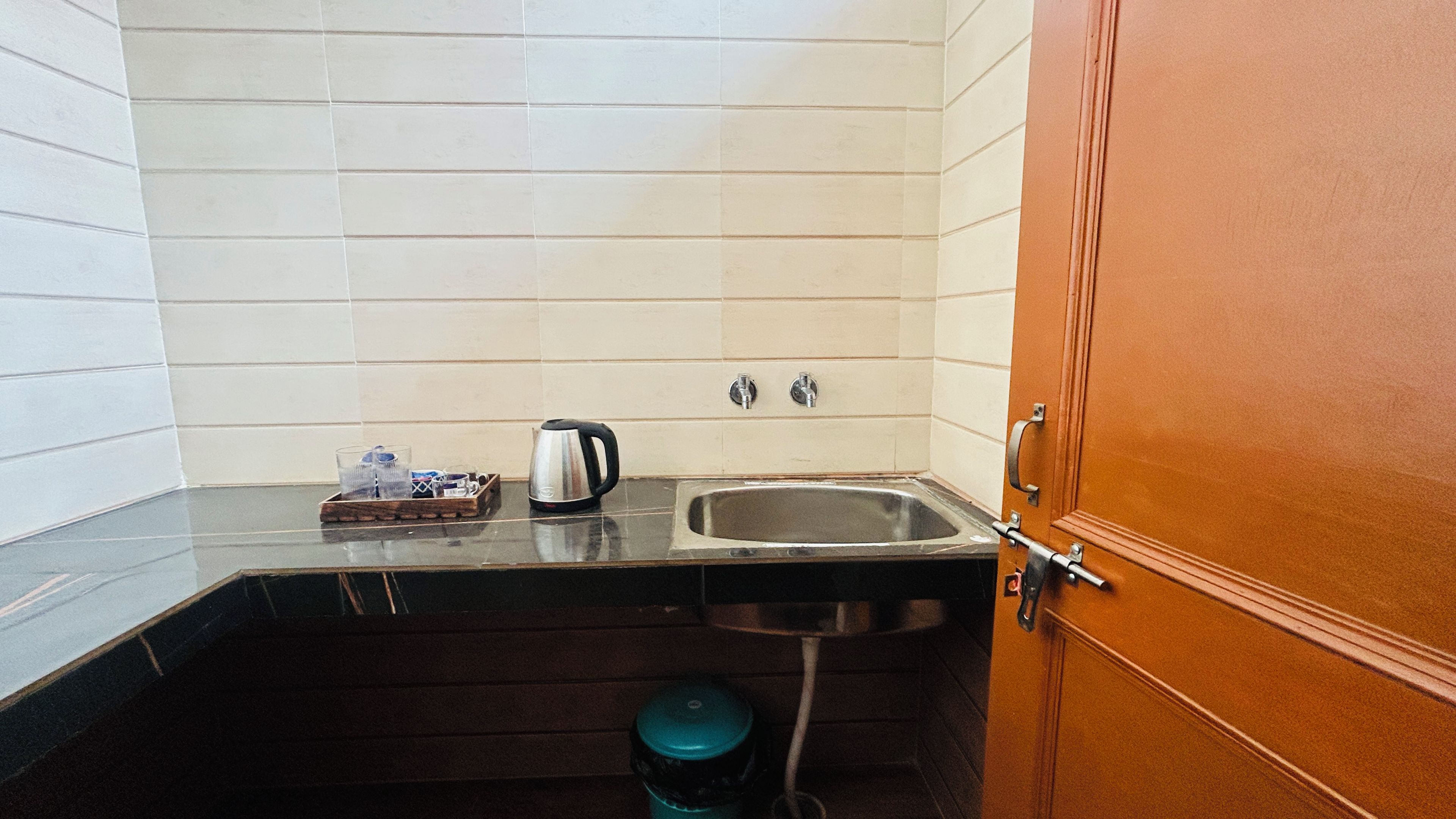 Een compacte kitchenette met een spoelbak, waterkoker en koffiezetapparaat.