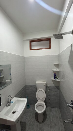 A bathroom with a toilet, sink, and shower.