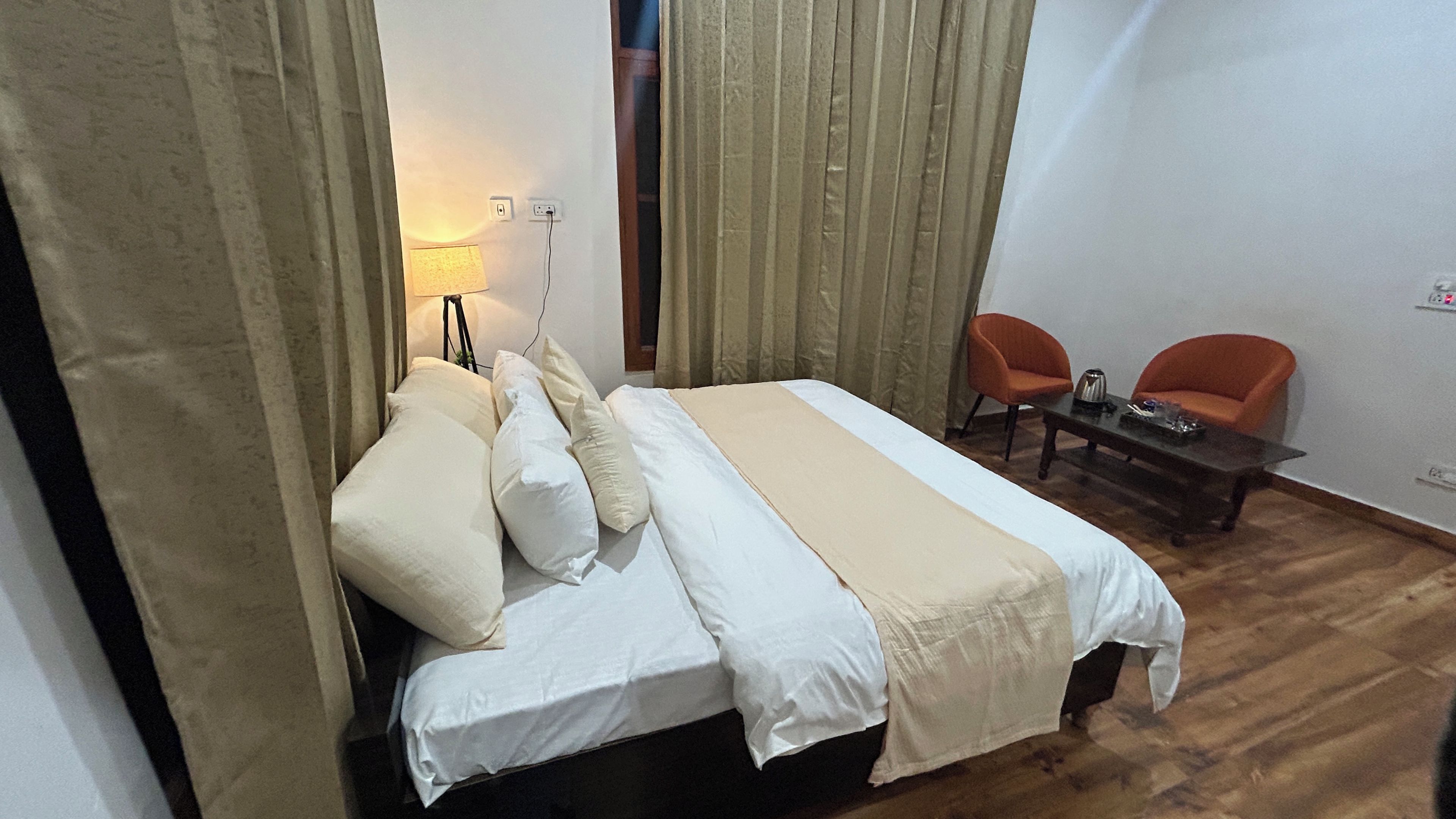 Een hotelkamer met een bed, twee stoelen, een klein tafeltje en een lamp.