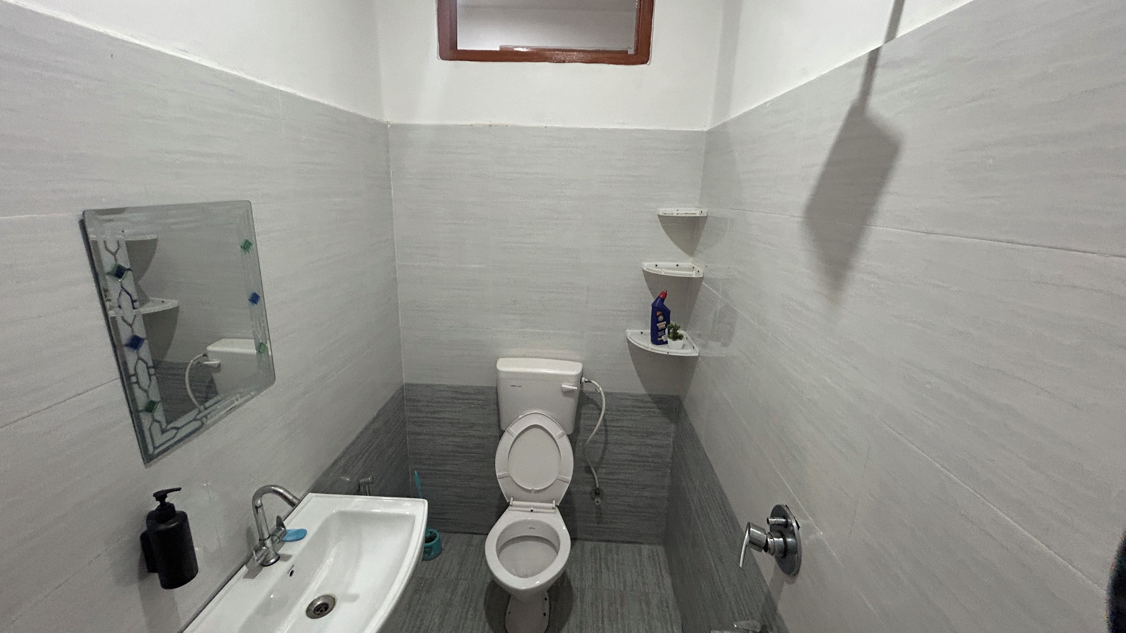 A small bathroom with a toilet, sink, and mirror.