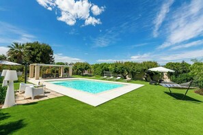 A swimming pool with a surrounding lawn, outdoor seating, and a pergola structure. - Villa with pool, hot tub and annexe in Bisceglie (Bisceglie)