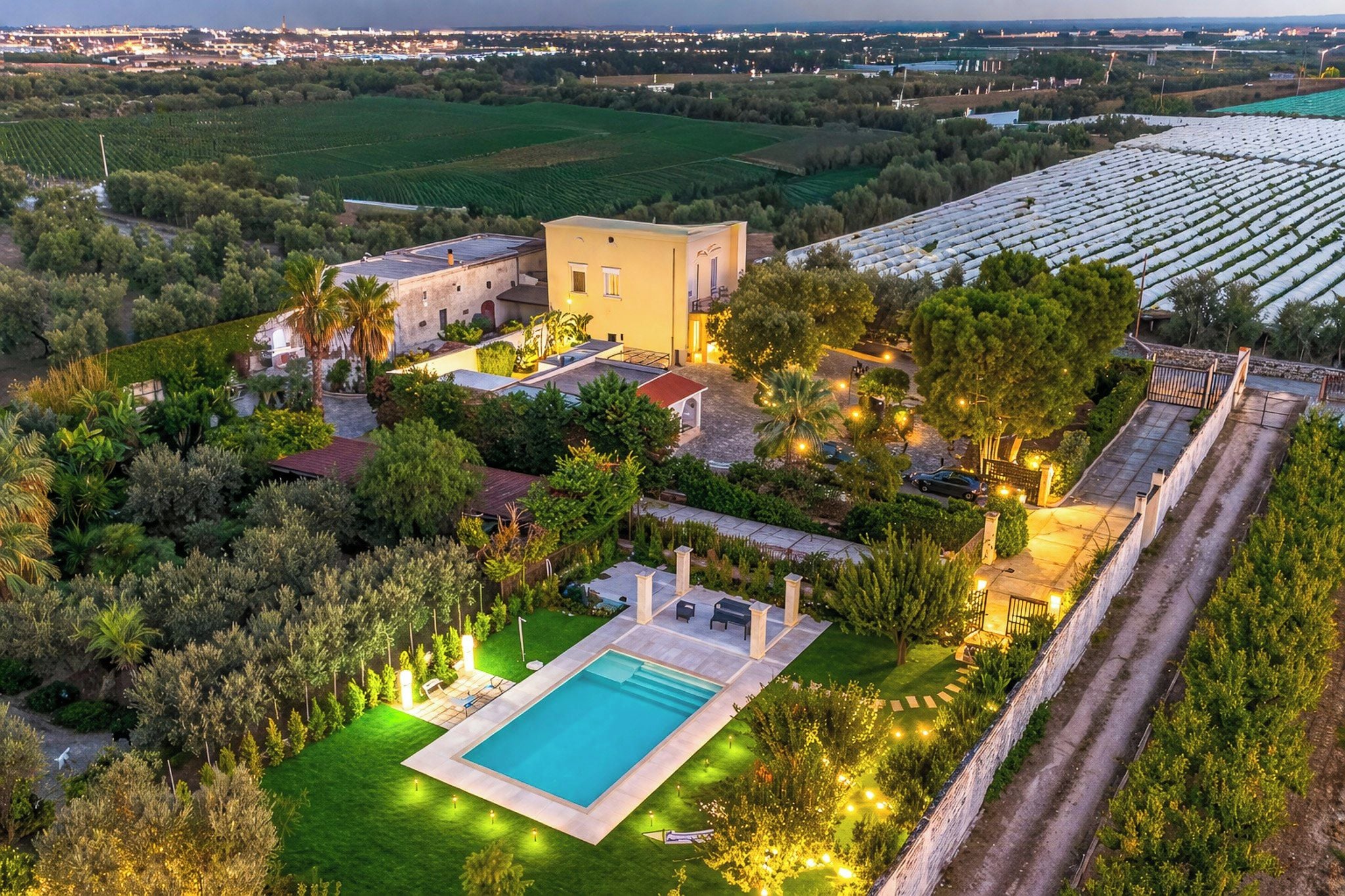 Una vasta proprietà con piscina, diversi edifici e ampi giardini.