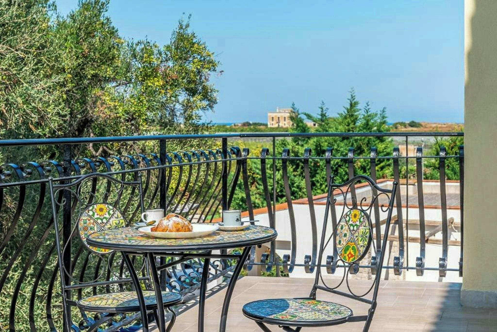 Un balcone con un tavolo apparecchiato per due, con un piatto di cibo e una tazza.