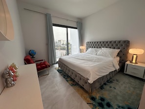 A modern hotel room with a large bed, two bedside lamps, a red chair, a globe, and a view of the city through the window. - ⁠Cozy 3BR Townhouse Walk to Music Bars & Pet-Friendly Restaurants⁠ (Dubai)