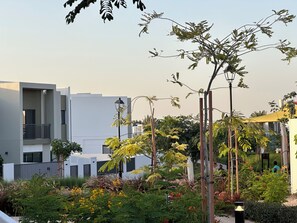 A modern building with balconies, surrounded by lush greenery and flowering plants. - ⁠Cozy 3BR Townhouse Walk to Music Bars & Pet-Friendly Restaurants⁠ (Dubai)