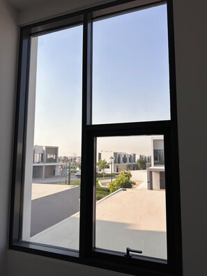 A window with a view of a modern building complex and a clear sky. - ⁠Cozy 3BR Townhouse Walk to Music Bars & Pet-Friendly Restaurants⁠ (Dubai)