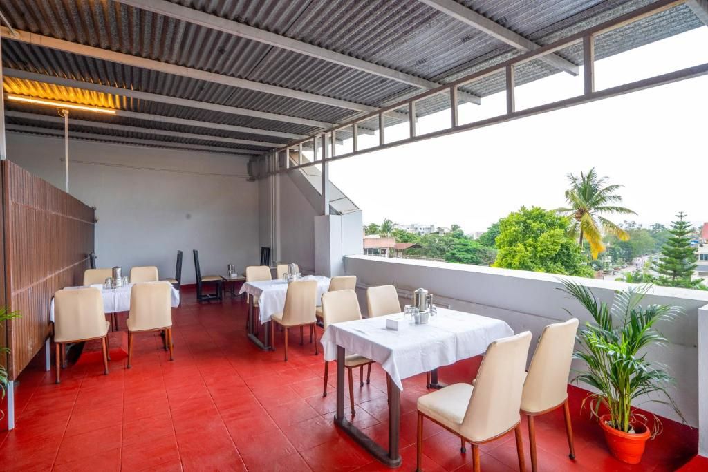 Un restaurante con mesas y sillas al aire libre, vistas a zonas verdes y edificios.