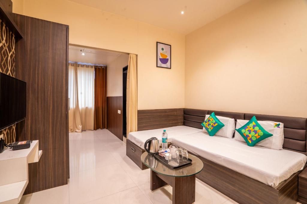 A hotel room with a sofa bed, a glass coffee table, a flat-screen TV, and a wall-mounted artwork.