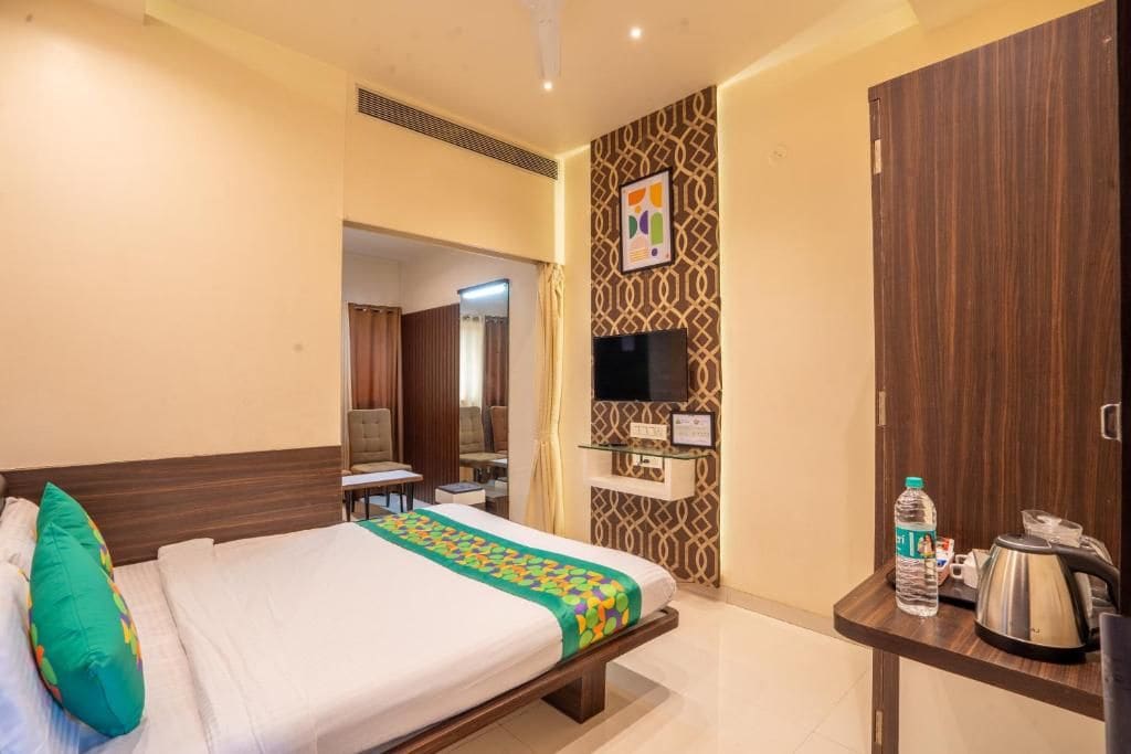 Habitación de hotel con cama, escritorio con hervidor, televisión y botella de agua.