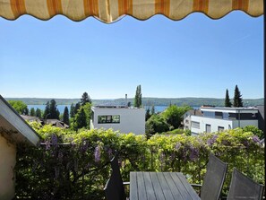 Ein Wohngebiet mit modernen Gebäuden, Blick auf einen See und ein Balkon mit Tisch und Stühlen.