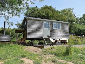 A rustic wooden cabin with a single door and windows, a chimney, and a small porch area. - 0 bedroom accommodation in West Bagborough, near Taunton (West Bagborough, near Taunton)