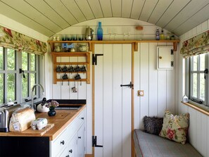 A kitchen with a wooden countertop, a sink, and a window with curtains. There is a shelf above the counter holding various kitchen items. - 0 bedroom accommodation in West Bagborough, near Taunton (West Bagborough, near Taunton)