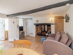 A cozy living room with a fireplace, a television, and a dining area with a table and chairs. - 1 bedroom accommodation in Knodishall, near Aldeburgh (Knodishall, near Aldeburgh)