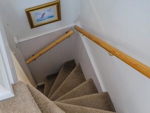 Eine Teppichstufen Treppe mit hölzernen Geländern und einem Bildrahmen an der Wand.