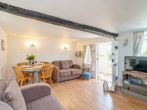 Ein gemütliches Wohnzimmer mit Holztisch, Sofas und einem Fernseher.