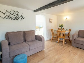 A living room with a sofa, a dining table with chairs, and a kitchen area in the background. - 1 bedroom accommodation in Knodishall, near Aldeburgh (Knodishall, near Aldeburgh)