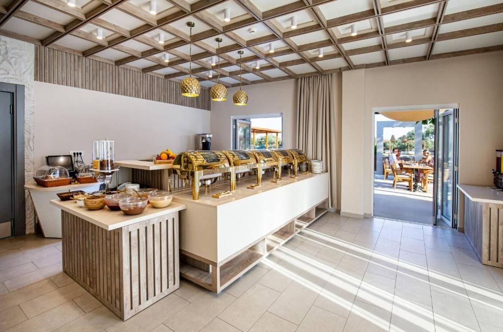 A modern hotel room with a breakfast bar, a kitchen area, and a view of the outdoor seating area.