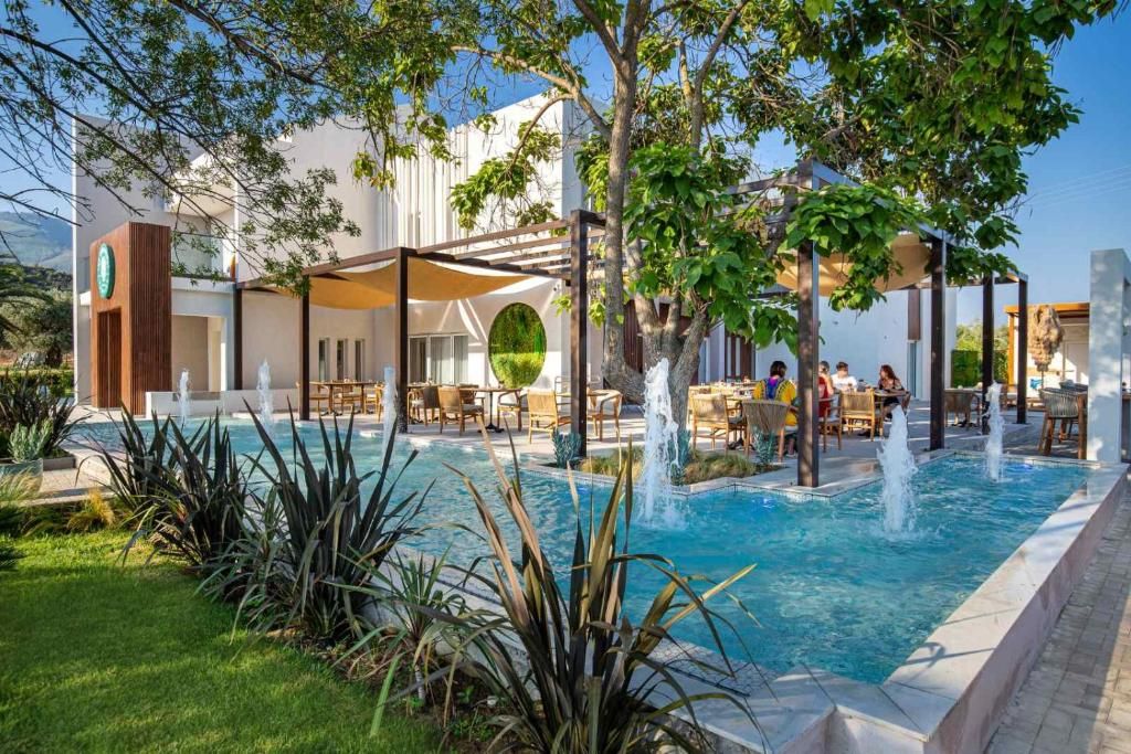 A pool area with a water fountain, outdoor seating, and a building with a modern design.
