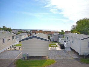 En række campingvogne med et picnicbord og en lille græsplæne foran.