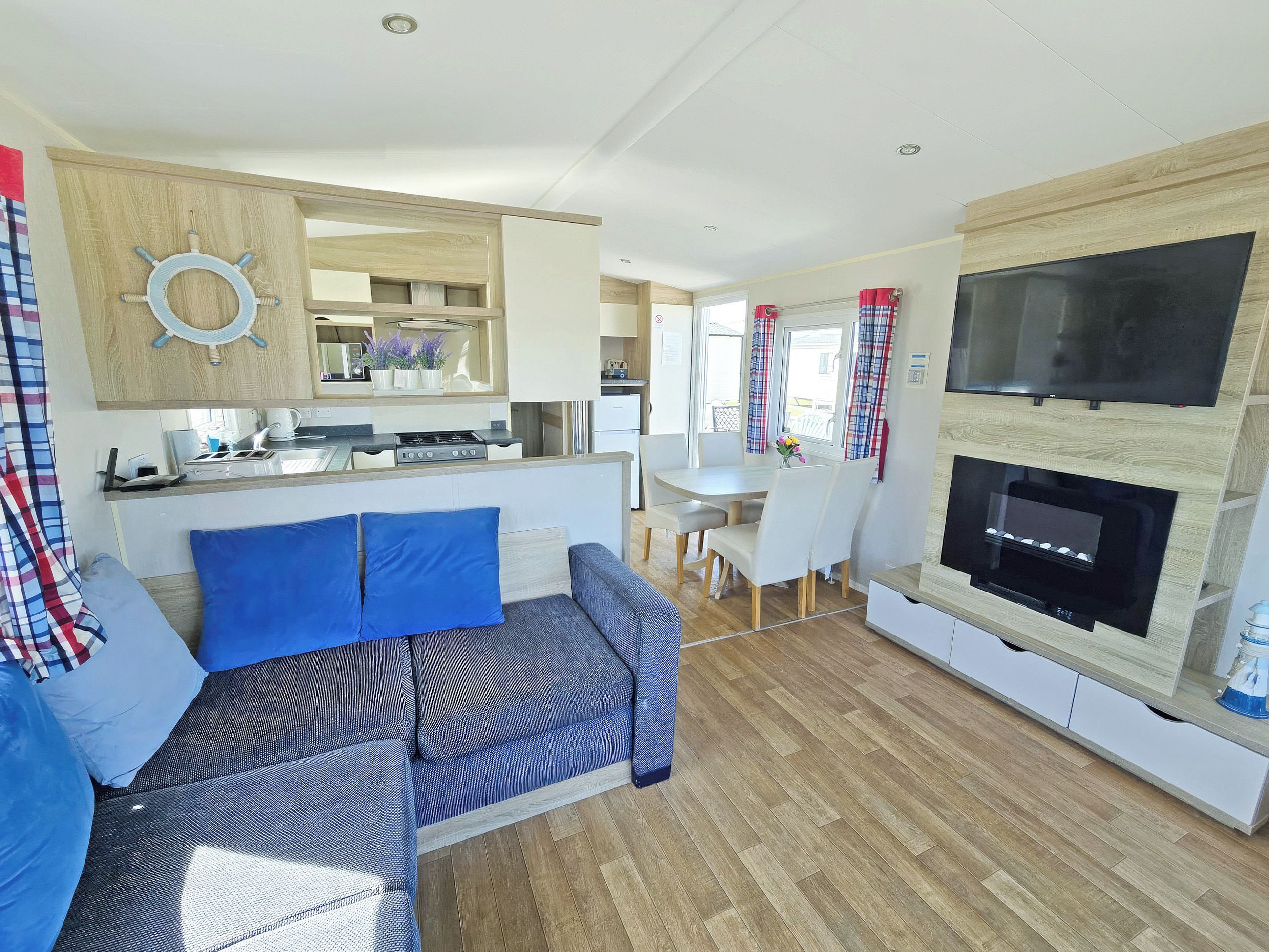 A modern living area with a sofa, dining table, and a TV mounted on a wooden wall.