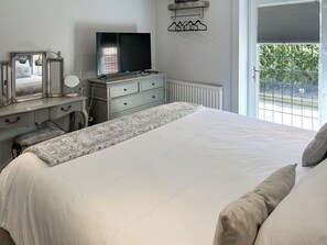 A bedroom with a bed, dresser, mirror, and television. - Springwood Cottage - UKC9437 (Holmesfield)