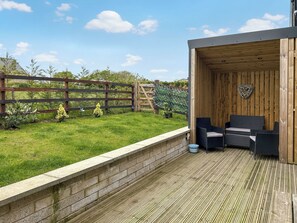 A wooden deck with a seating area, a brick wall, and a wooden fence. - Merlyn Barn - UKC9439 (Holmesfield)
