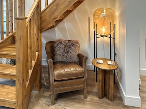 A wooden staircase, a leather armchair with a fur throw, and a floor lamp with a glass shade. - Merlyn Barn - UKC9439 (Holmesfield)