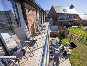 Eine Terrasse mit Gartenmöbeln, einem Whirlpool und Blick auf eine Wohngegend.