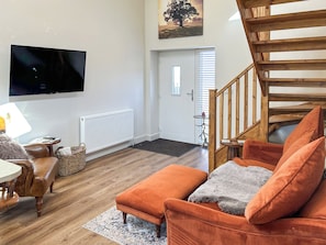 A living room with a wooden floor, a sofa, a television, and a staircase. - Forest Barn - UKC9438 (Holmesfield)