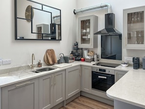 A modern kitchen with grey cabinets, a stainless steel sink, a black range hood, and a built-in oven. - Forest Barn - UKC9438 (Holmesfield)
