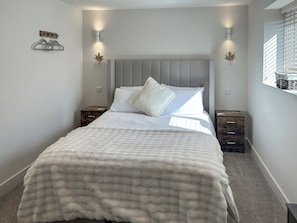 A bedroom with a bed, two bedside tables, a wall-mounted light fixture, and a window with blinds. - Forest Barn - UKC9438 (Holmesfield)
