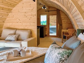 A cozy wooden interior with a sofa, a dining area, and a view through a door. - Laurel Lodge - UKC9519 (Gillingham, near Beccles)
