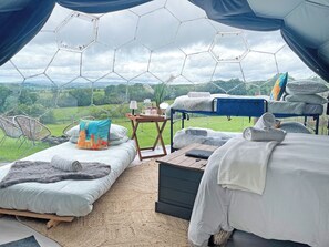 A tented accommodation with two beds, a table, and a view of the countryside. - Ingleborough Dome - UKC9594 (Clitheroe and the Ribble Valley)