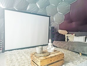 A room with a projector screen, a sofa, a meditation statue, and a wooden crate with a woven mat. - Ingleborough Dome - UKC9594 (Clitheroe and the Ribble Valley)