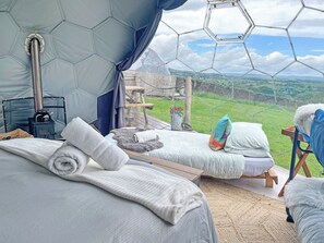 A cozy room with two beds, a wooden table, and a view of the countryside. - Ingleborough Dome - UKC9594 (Clitheroe and the Ribble Valley)