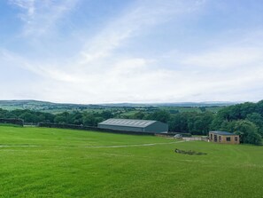 A rural landscape with a barn, a stone wall, and a path leading to a wooden structure. - Malham Dome - UKC9597 (Earby)
