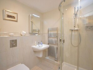 Une salle de bain moderne avec une douche à parois de verre, un lavabo équipé de produits de toilette et un porte-serviettes.