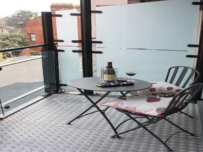 A balcony with a table, chairs, a bottle of wine, and a glass of wine. - 2 bedroom accommodation in Whitby (Whitby)