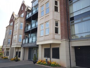 A multi-story hotel with a prominent entrance, a balcony on the second floor, and a parking area with flower beds. - 2 bedroom accommodation in Whitby (Whitby)